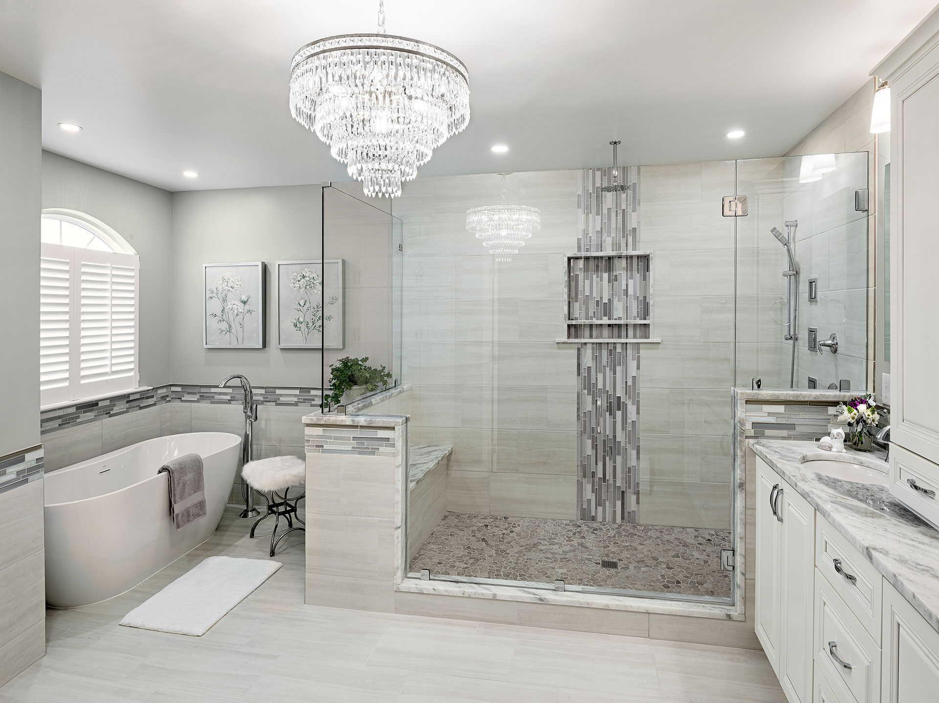 A photo of a luxurious and sleek bathroom with a freestanding bathtub, a glass-enclosed shower, a modern vanity with double sinks, and marble tiles on the walls and floor.
