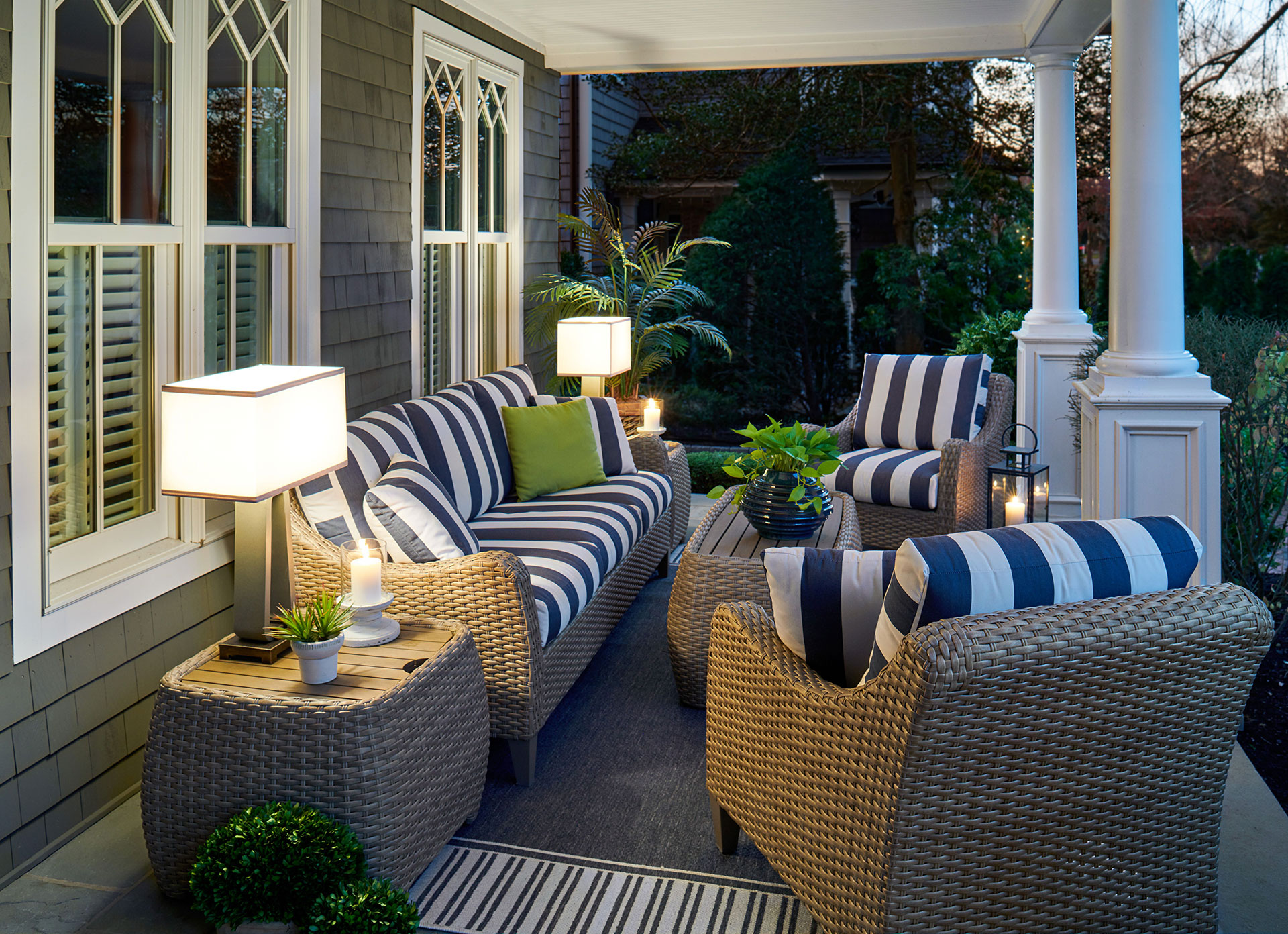 A photo of an outdoor living space with a comfortable sofa, a table, and two chairs surrounded by greenery.
